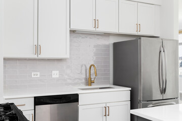 Wall Mural - A kitchen detail with white cabinets, gold faucet and hardware, subway tile backsplash, and white quartz countertops. No brands or labels.