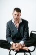 © Elina Leonova - Handsome man, fashion model sits on chair barefoot