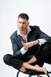 © Elina Leonova - Handsome man, fashion model sits on chair barefoot