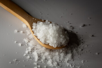 Organic rock salt in wooden spoon on white background. Transparent, healthy rock salt extracted in Turkey.