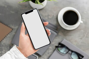 Wall Mural - Hand holding smartphone mockup of blank screen on the table. Take your screen to put on advertising. Hand holding smartphone mockup of blank screen on the table. Take your screen to put on advertising