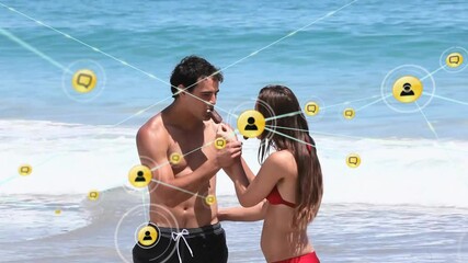 Wall Mural - Animation of network of connections with icons over caucasian couple on beach