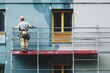 © vasyan_23 - Construction worker painting building exterior on scaffolding with safety gear