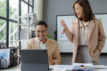 Wall Mural - Two business partners sharing a laugh while working on a project