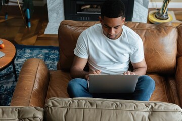 Wall Mural - You can shop just about anything online Cropped shot of a young man using a laptop while relaxing on the sofa at home