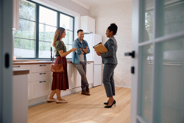 happy black real estate agent and couple in the kitchen of new house.