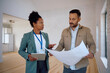 © Drazen - Black real estate agent and her client analyzing blueprints of  new house.
