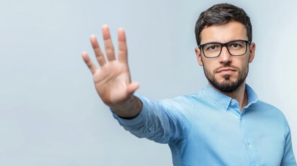 Businessman in blue shirt showing stop gesture with hand against white background