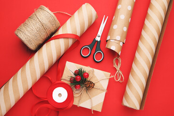 Canvas Print - Rolls of craft papers with gift box and scissors on red background