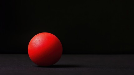 Canvas Print - A solitary red ball rests on a dark surface, creating a minimalist aesthetic.