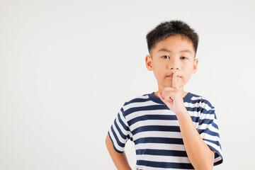 Young kid boy making finger on lips mouth silent quiet gesture, Happy Asian primary child marking silence for stop quiet, mute studio shot isolated on white background with copy space