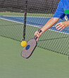 © Jo - Female pickleball player about to hit a pickleball with paddle