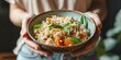© AkuAku - Woman holding a bowl of Turkish or Levantine Arabic vegetable bulgur pilaf a nutritious vegan and vegetarian dish