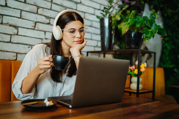 Young caucasian woman working or studying on laptop from cafe 