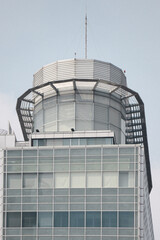 Close-up of a contemporary tower's rooftop with sleek steel structures and a glass facade, showcasing modern architecture with geometric patterns and minimalist design