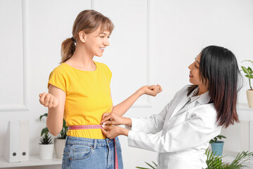 Sticker - Female Asian nutritionist measuring patient's waist in office