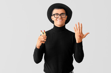 Poster - Male makeup artist with lipsticks on light background