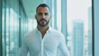 © tashechka - A confident businessman in a white shirt strides confidently through a sleek office with panoramic views of the city