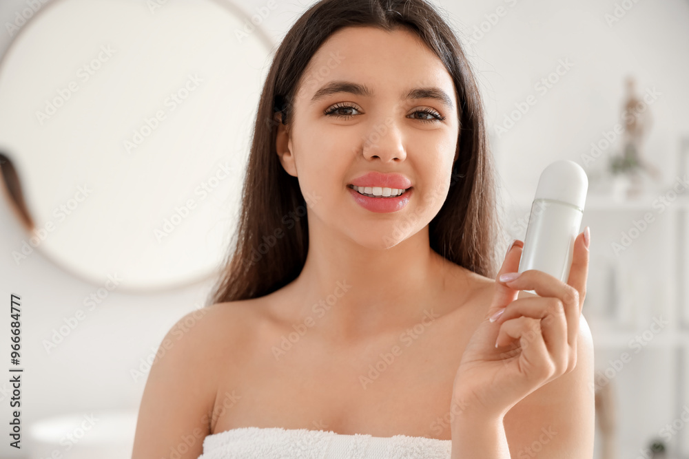 Young woman with roll-on deodorant in bathroom, closeup
