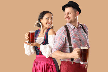 Wall Mural - Happy mature waiters in traditional German clothes with mugs of beer on beige background