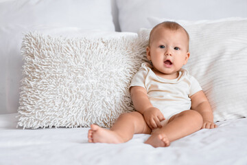 Sticker - Cute little baby sitting on bed in room at home