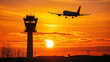 © Creativision - Silhouette of an airplane flying over the control tower at sunset