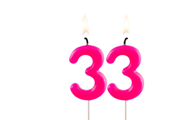 Wall Mural - Pink number 33 birthday candle lit on white background