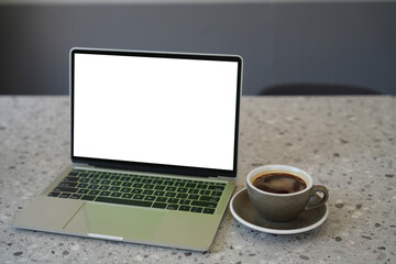 Laptop computer with blank white screen with coffee cup on table. Working business concept.