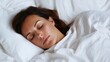 © JAYDA RIN - A peaceful woman sleeping comfortably in a cozy bed, surrounded by fluffy white blankets, exuding tranquility and relaxation.