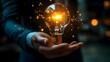 © Siasart Stock - A hand holding a glowing light bulb with sparkling effects, symbolizing ideas and innovation.