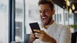 © Pascal - Young successful excited business man reading great news in mobile message. Happy male investor celebrating financial money market growth using smartphone looking at cell phone working in office.