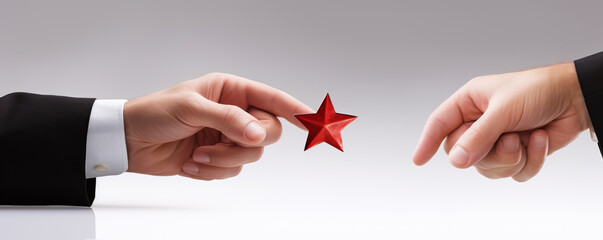 Two hands reaching towards a red star on a smooth surface during a symbolic moment of collaboration