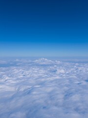 Poster - A snowy mountain peak peeks through a vast sea of fluffy white clouds.