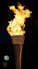 Sticker - A close-up of a lit torch with a large flame against a dark background.