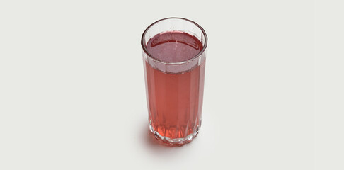 A glass of traditional Ukrainian compote is presented on a white background. The vibrant red color of the drink is made from a blend of fresh berries and fruits