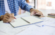 © Lek - Asian man hands holding pen taking note checking income and expenses from financial document and use mobile doing online business after start new business owner