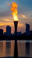 Poster - A large torch burns brightly against the backdrop of a city skyline at sunset.