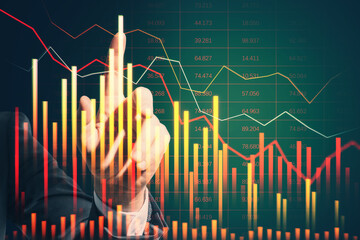 Wall Mural - Close up of businessman hand pointing at falling business chart on blurry background. Crisis and market concept.