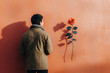 © Irina B - A man standing with his back turned, facing an orange wall, with a single orange rose pinned beside him.