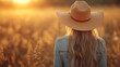 © D-stock photo - A girl in a straw hat walks through the field at sunset.