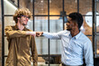© Art_Photo - Two diverse businessmen fist bump in modern office, professional greeting, teamwork and collaboration, multicultural business environment, positive work relationship, success, trust and partnership