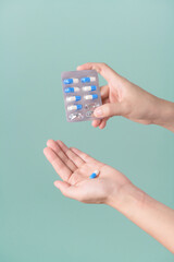 Medical pills. woman hands removing pills from panel on green background.