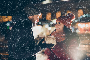 Canvas Print - Photo of two charming people with hot tea beverage in hands celebrating x-mas eve in magic outdoors atmosphere wearing warm jackets