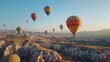 © Quickknow - Aerial view of colorful hot air balloons floating over the dramatic landscapes of Cappadocia, with a clear blue sky in the background