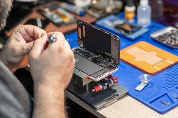 Aufkleber - A skilled technician performs phone repair and replaces a battery in a well-organized workshop with tools and parts readily available