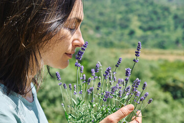 Woman inhales the aroma blooming scented lavender flowers. Natural herbal methods of treatment. Alternative medicine. Lavender essential oil. Aromatherapy.