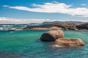 Western Australia, Green's Pool in Denmark, rocky coastline with clear water and distant waves under a partly cloudy sky.