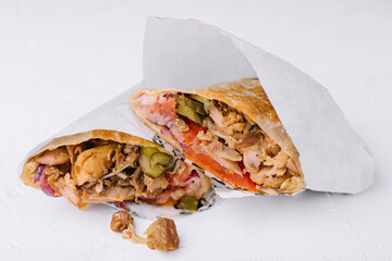 Delicious chicken shawarma lying on white background