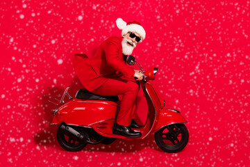 Poster - Photo of charming funky mature motorcyclist dressed christmas costume hat smiling hurrying isolated red color background