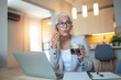 © Dragana Gordic - Senior Woman Working Remotely While Drinking Coffee at Home